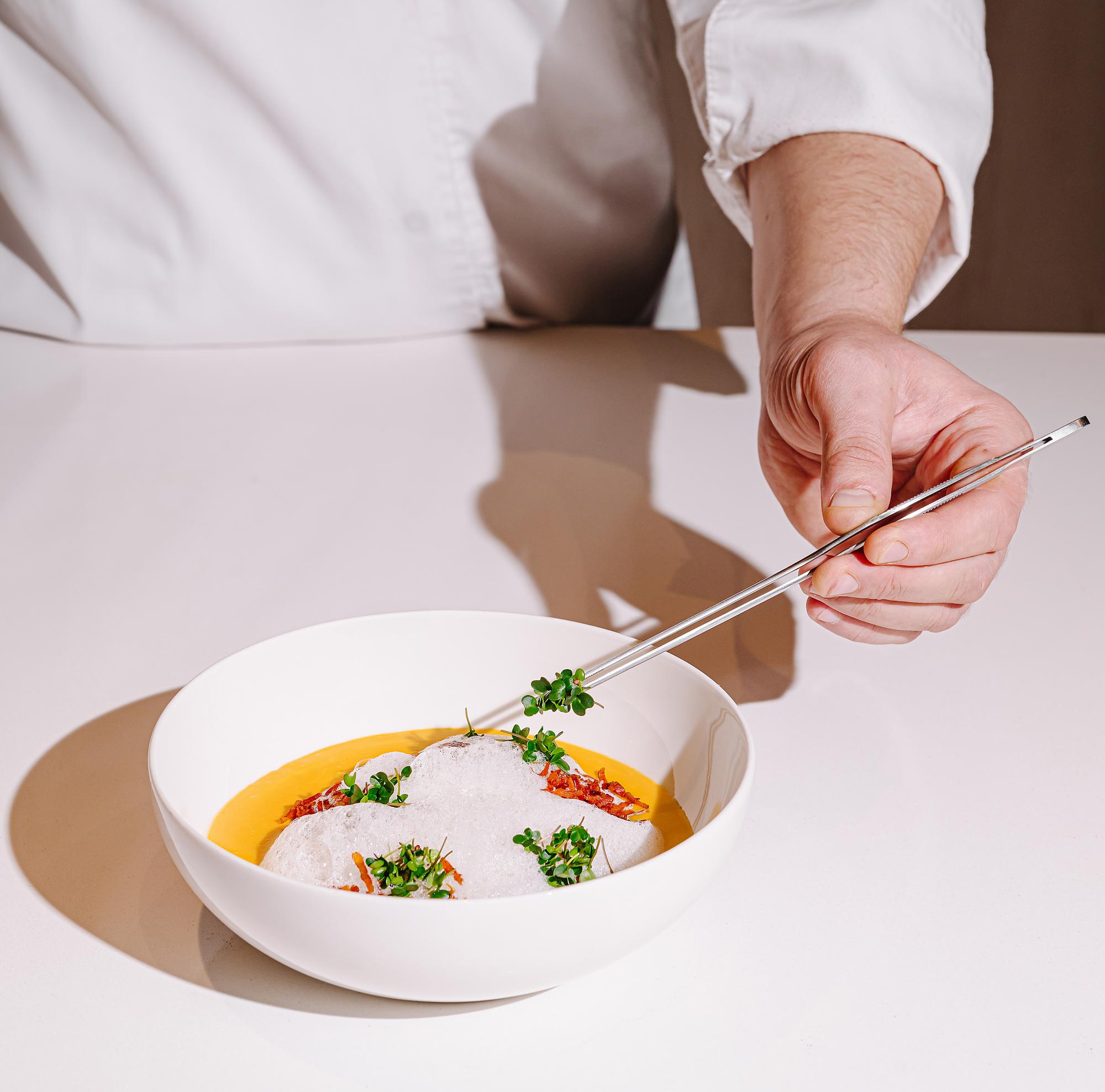 chef arranging plated seasonal dish on wooden table